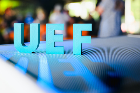 UEF kirjaimet tason päällä, edustalla kirjaimista muodostuva varjo