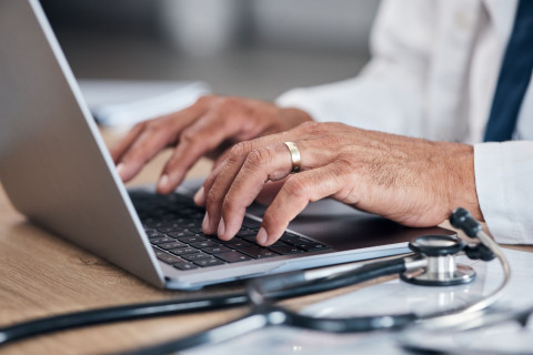 Lääkärin kädet kannettavan tietokoneen näppäimistöllä.