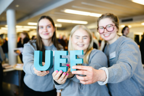 Kolme henkilöä pitää sormissaan UEF-kirjaimia.