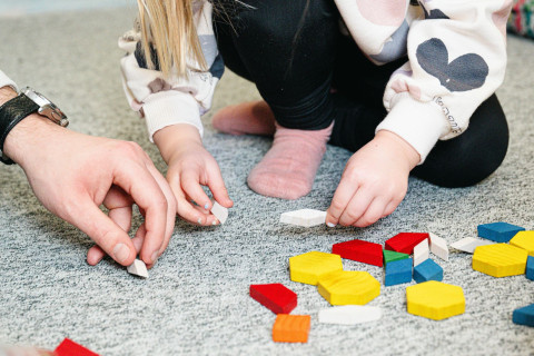 Lapsi leikkii alakoululla aikuisen kanssa.