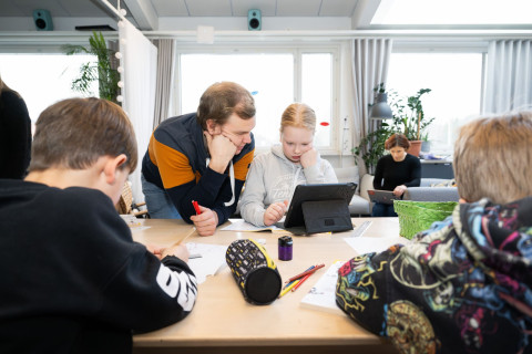 Opettajat tekemässä koululaisten kanssa tehtäviä.