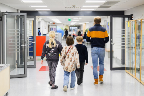 Alakoulun oppilaat kävelemässä opettajan kanssa käytävällä.