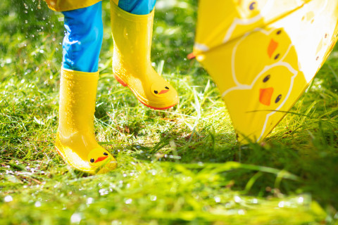 Lapsi kumisaappaissa ja sateenvarjon kanssa.