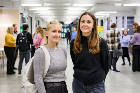 Saara Torpakko ja Miia Prusi seisovat yliopiston aulassa.