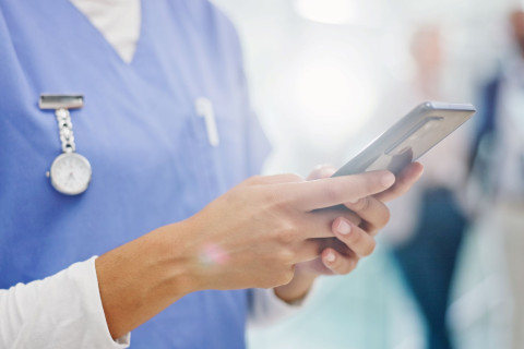 Sairaanhoitaja selaa matkapuhelinta.