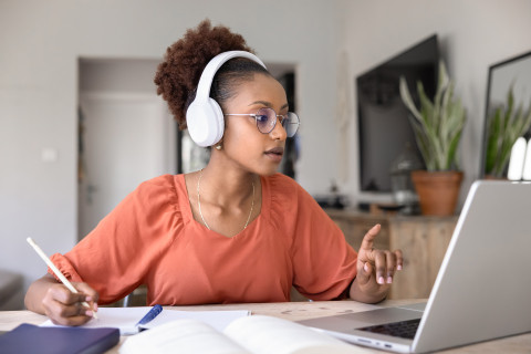 Opiskelija kuulokkeet päässä tietokoneen ääressä.