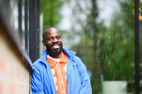Student leaning on a wall and smiling