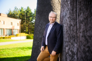 Jyrki Huusko nojaa puuhun.