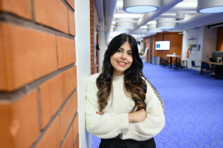 Student standing in a corridor and smiling