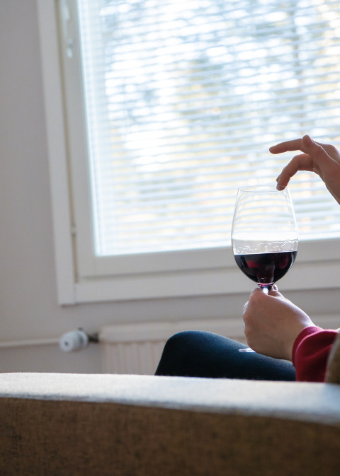 Photo of a person holding a glass of red wine.