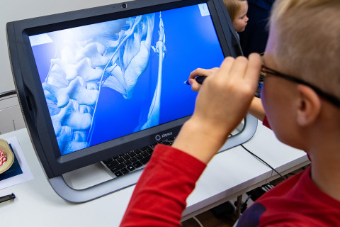 Nuori poika harjoittelee tietokoneohjelman avulla mikrokirurgista toimenpidettä.