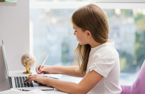 A child studying with the laptop on the table.