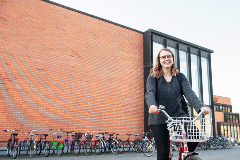 Opiskelija pyöräilemässä kampuksella