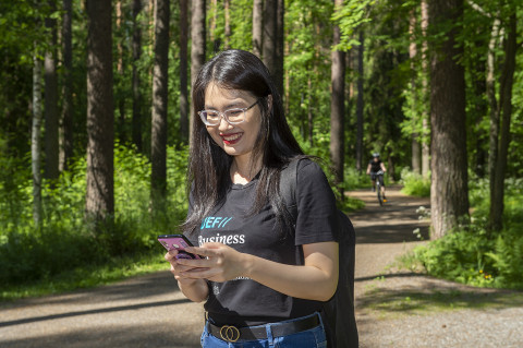 Young woman outside, holding a mobile phone.