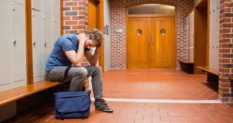 Surullinen opiskelija istuu penkillä.