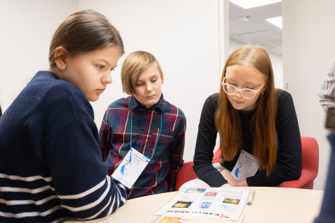 Kolme oppilasta ratkaisemassa pakohuonepeliä.