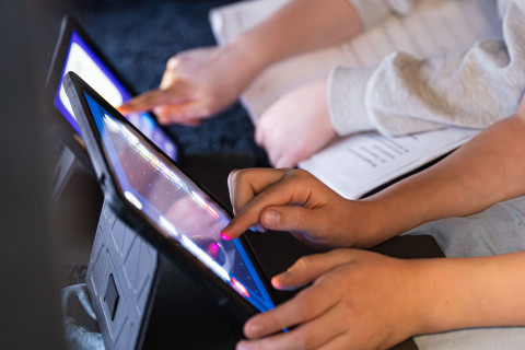 Käsiä tietokoneiden näytöllä.