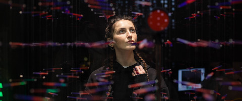 Henkilö punertavien valoheijastusten keskellä pimeässä