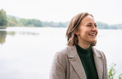 Young woman smiling, lake view behid her.