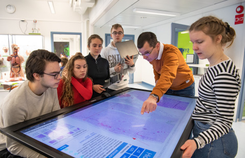 Teacher showing students a virtual sample on a touch screen.