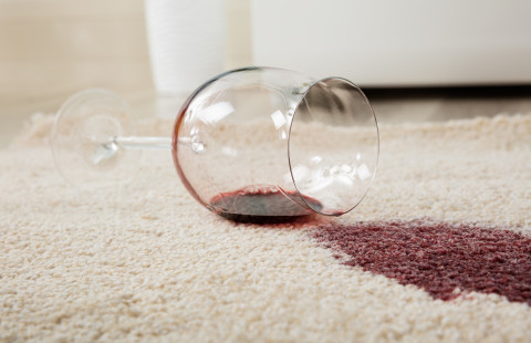 Red wine spilled from glass on carpet