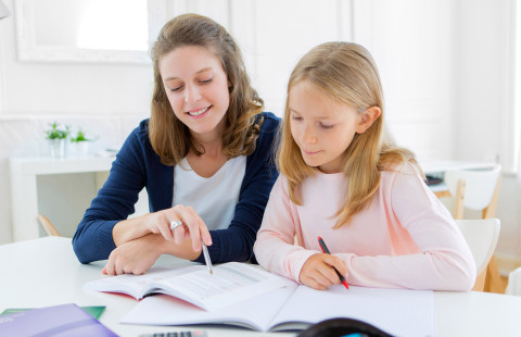 Äiti neuvoo lasta läksyissä.