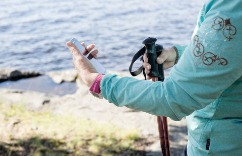 Person with Nordic walking poles looking at mobile phone