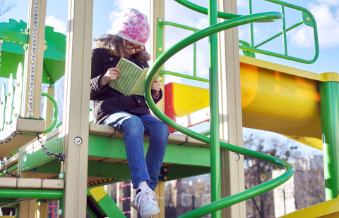 Lapsi lukee leikkipuistossa.