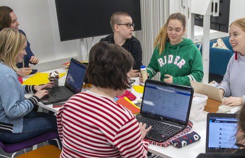 Opiskelijoita pöydän ympärillä.