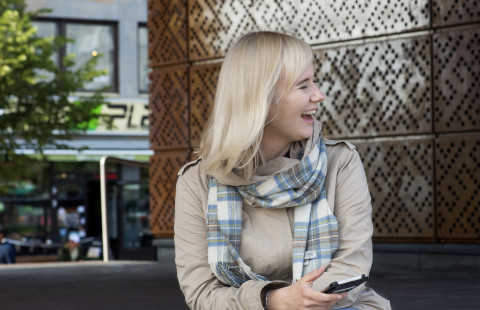 Opiskelija selaa puhelinta ja nauraa