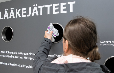 Nainen pudottaa vanhentuneita lääkkeitä lääkejätesäiliöön.