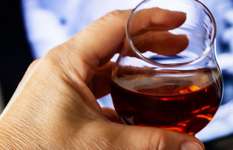 Hand holding a glass of alcohol.