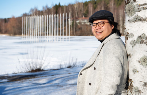 Young man outside in wintery scenery, smiling.