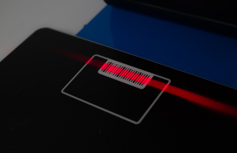 Lainausautomaatin viivakoodilukijan punainen säde mustalla pohjalla.