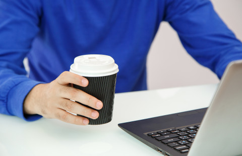 Hands holding coffee and laptop