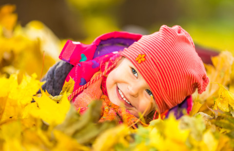 Lapsi leikkii syksyn lehdillä