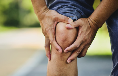 Man holding an aching knee.