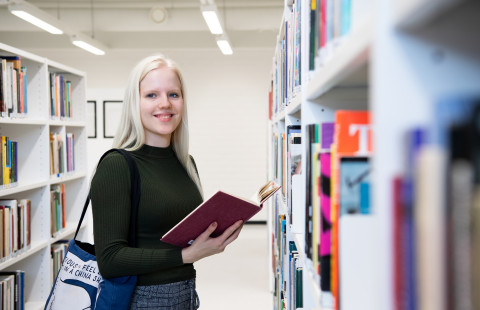 Naispuolinen opiskelija lukee kirjaa UEFin kirjastossa.