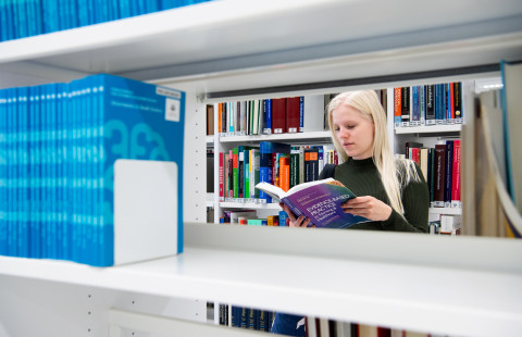 Opiskelija lukee kirjaa UEFin kirjastossa.