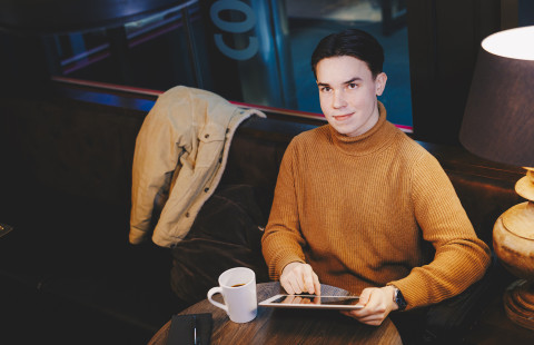 Nuori mies istuu kahvilassa