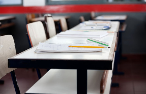 Vihkoja ja kyniä koulupöydällä