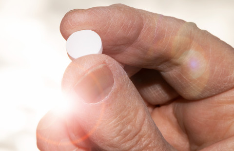 Hand holding a vitamin D pill.