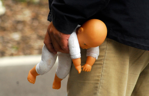 Mies puristaa nukkea kädessä