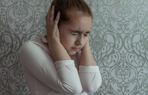 A girl covers her ears