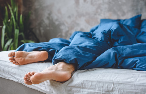 Nukkuvan henkilön jalat pilkistävät peiton alta