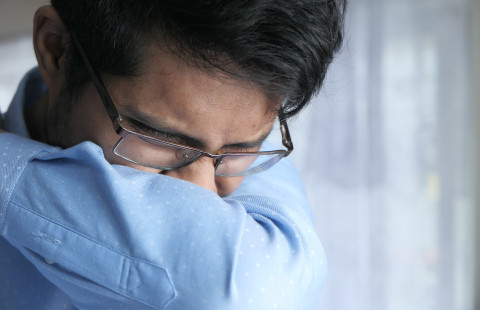 Man coughing into sleeve