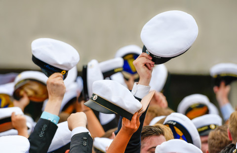 Opiskelijat heiluttavat ylioppilaslakkejaan.