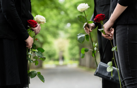 Surevat omaiset ruusujen kanssa hautajaisissa.