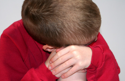 Surullinen poika nojaa polveensa.