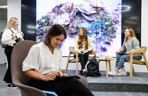 Neljä naisopiskelijaa istuu yliopiston oleskelutiloissa.